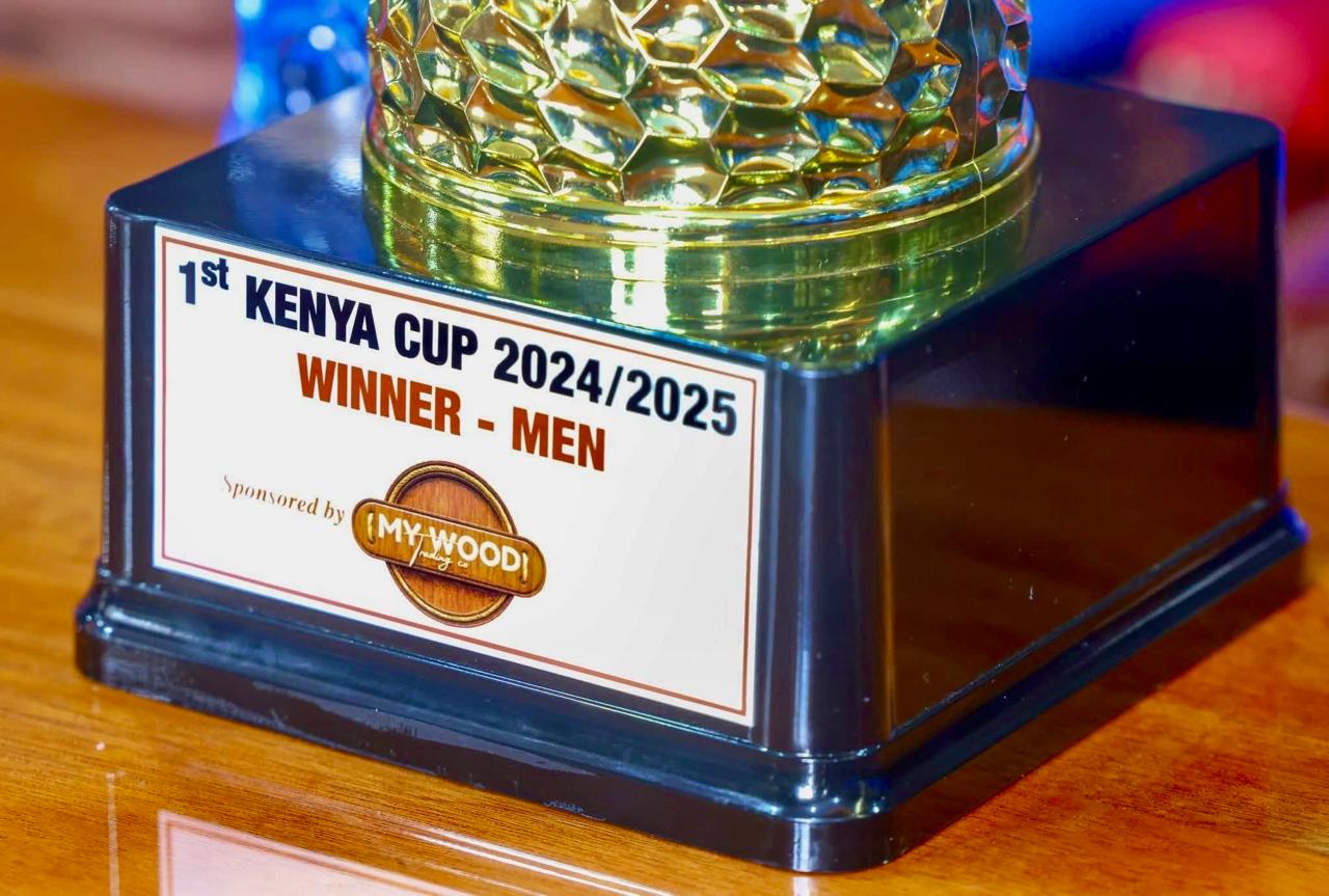 Close-up of a trophy labeled “1st Kenya Cup 2024/2025 Winner - Men,” sponsored by My Wood Trading Company, featuring a gold-patterned top and black base placed on a wooden surface.