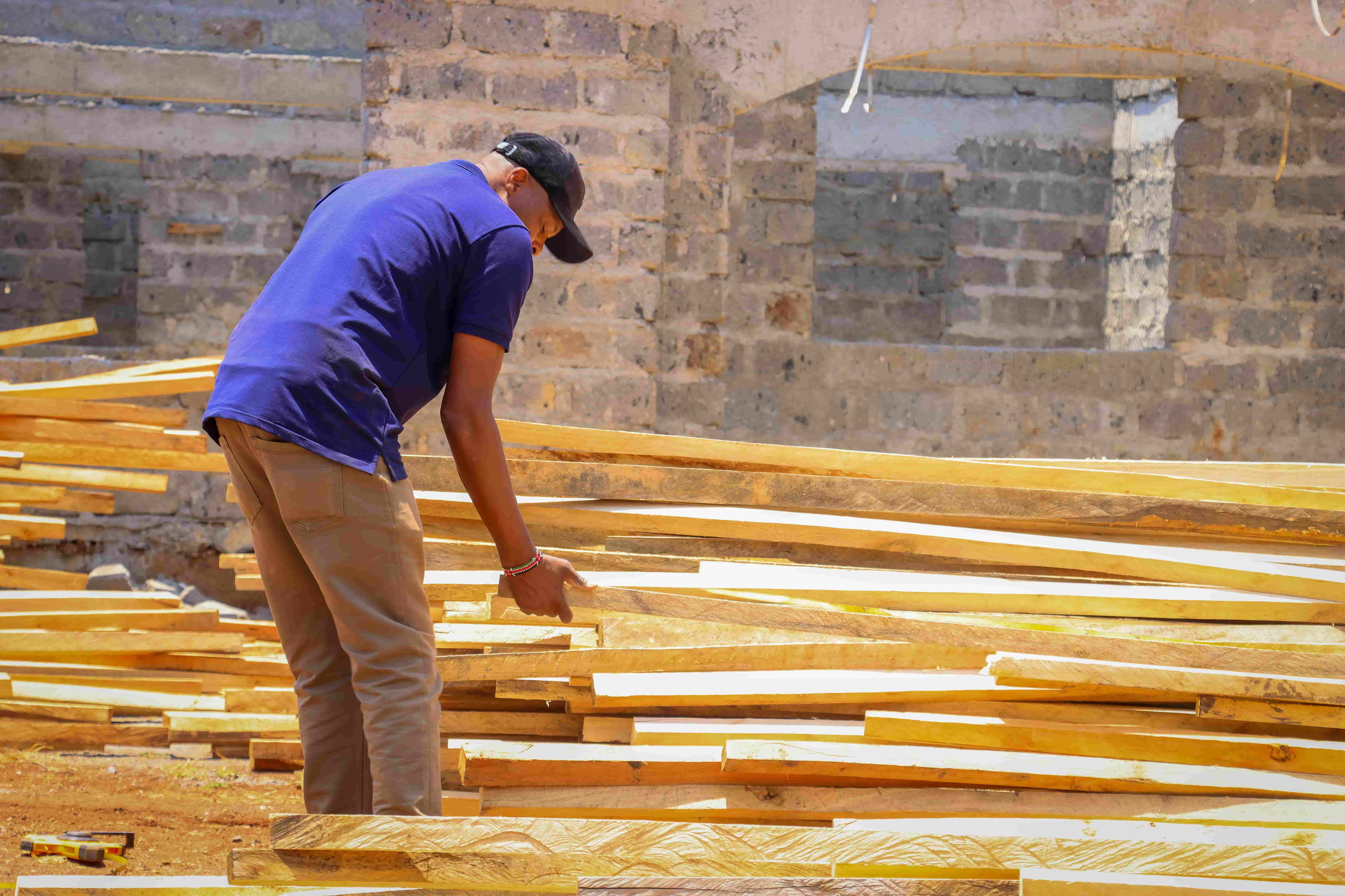 man_inspecting_wood_planks_construction_site_oct_2025